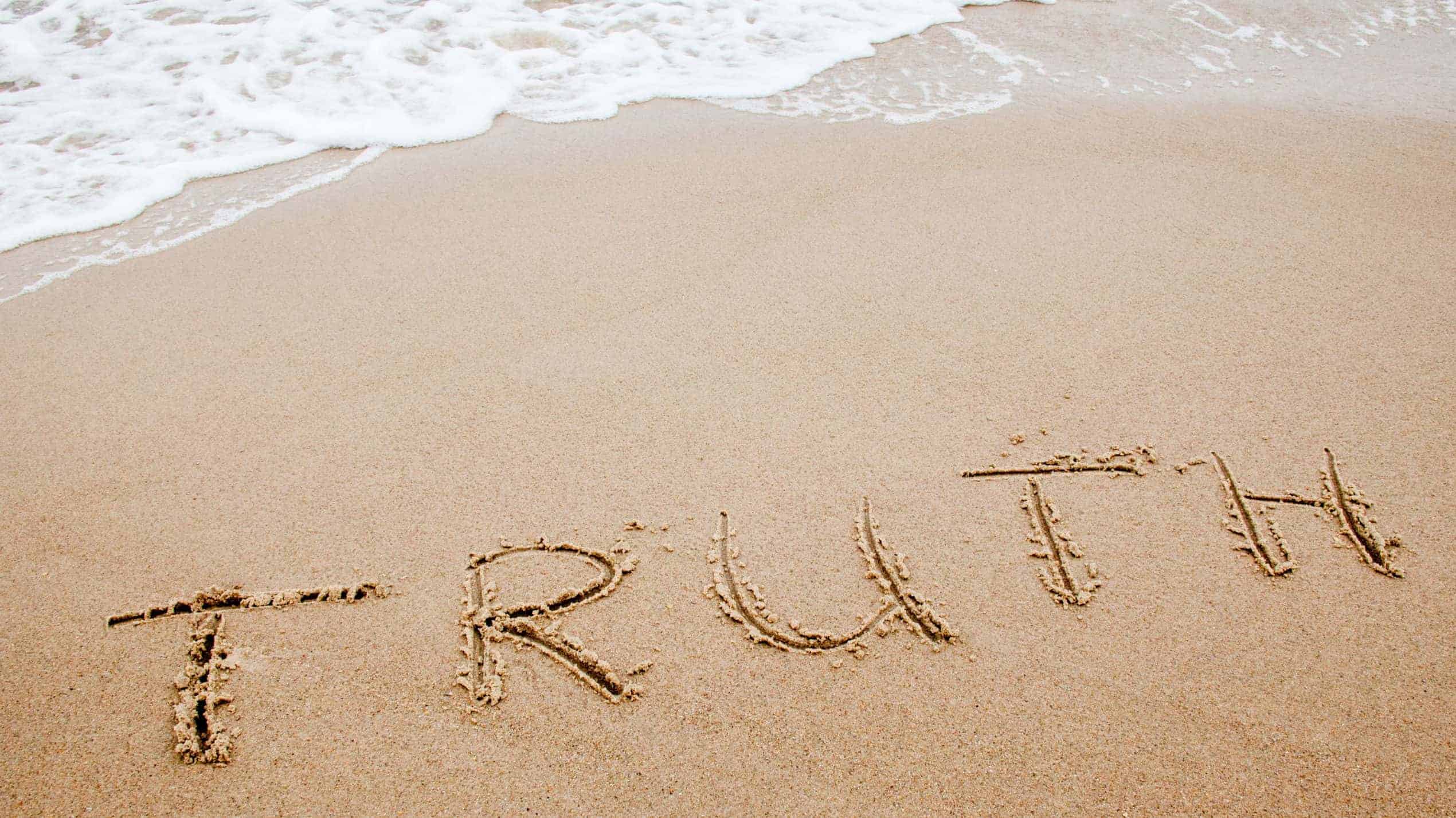 Word truth written on the sand
